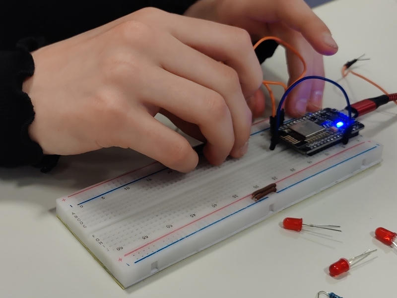 Hände eines Kindes, die Drähte und LEDs auf ein Breadboard mit einem ESP stecken
