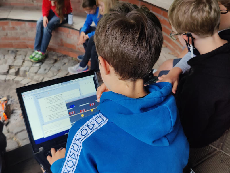 Kinder mit Laptops an einer Lagerfeuerstelle