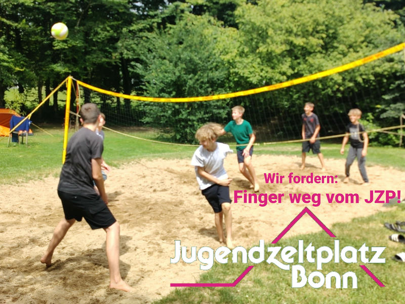 Kinder beim Volleyballspielen auf einem Beachvolleyballfeld mit Wiese