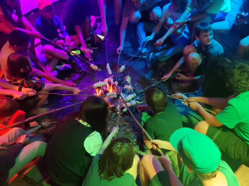 Kinder an einem bunt beleuchteten Lagerfeuer