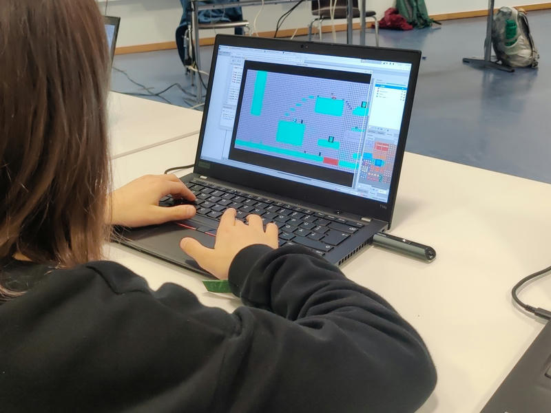 Blick über die Schulter eines Kindes, das an einem Laptop den Map-Editor Tiled bedient