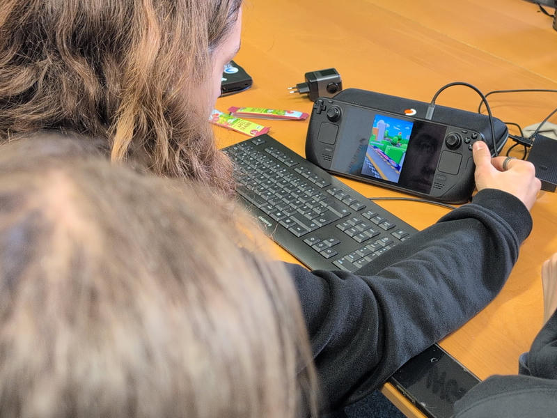 Zwei Köpfe 
schauen auf ein Steam Deck.